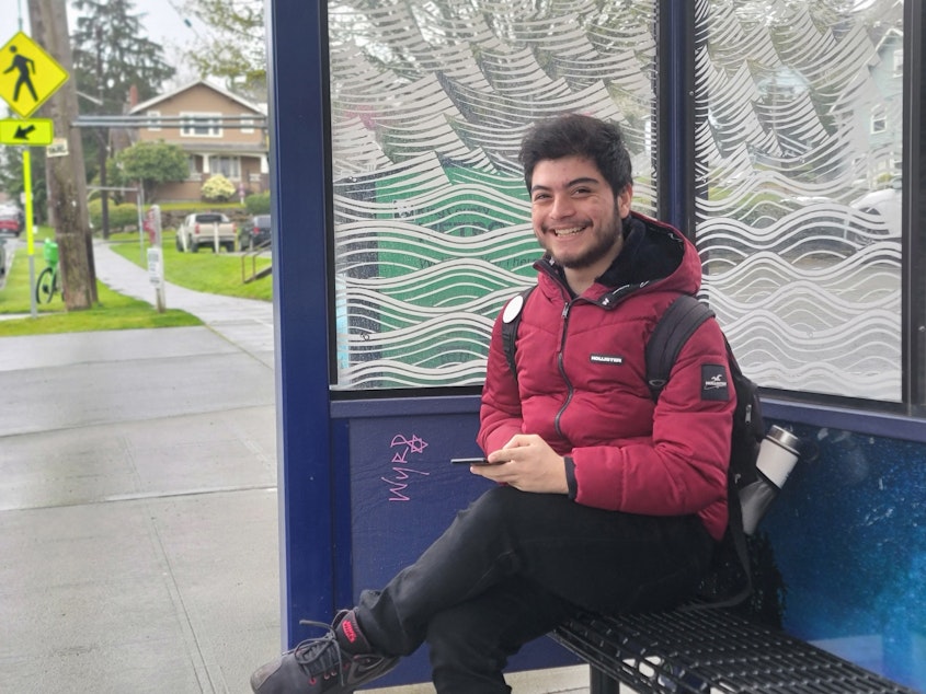 caption: Fabian Hernandez-Angel at the bus stop he uses to return home from school on April 20, 2023 at Seattle Pacific University.