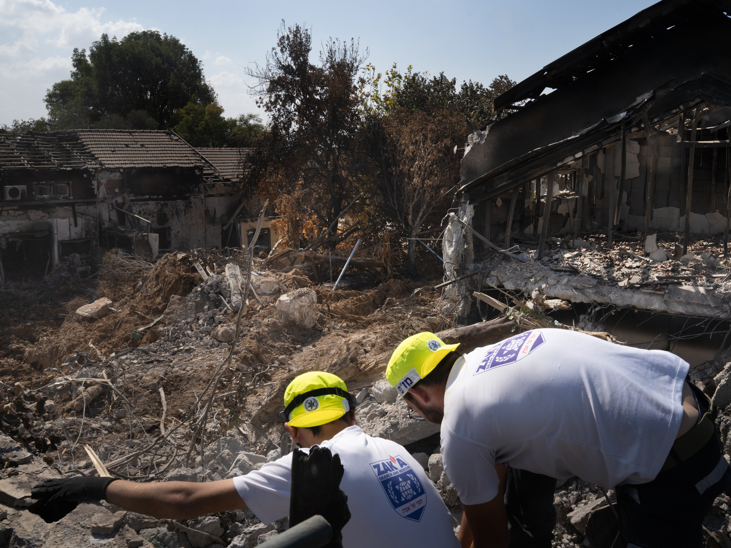caption: Men working with a search and recovery team from the organization ZAKA look for human remains in Kibbutz Be'eri.