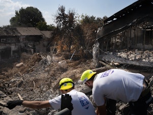 caption: Men working with a search and recovery team from the organization ZAKA look for human remains in Kibbutz Be'eri.