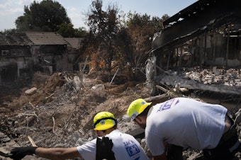 caption: Men working with a search and recovery team from the organization ZAKA look for human remains in Kibbutz Be'eri.