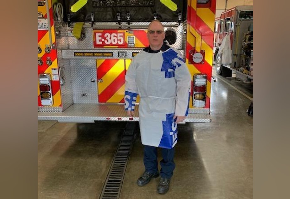 caption: Firefighter Jim Wilson models a protective gown he made out of construction-grade vapor barrier.
