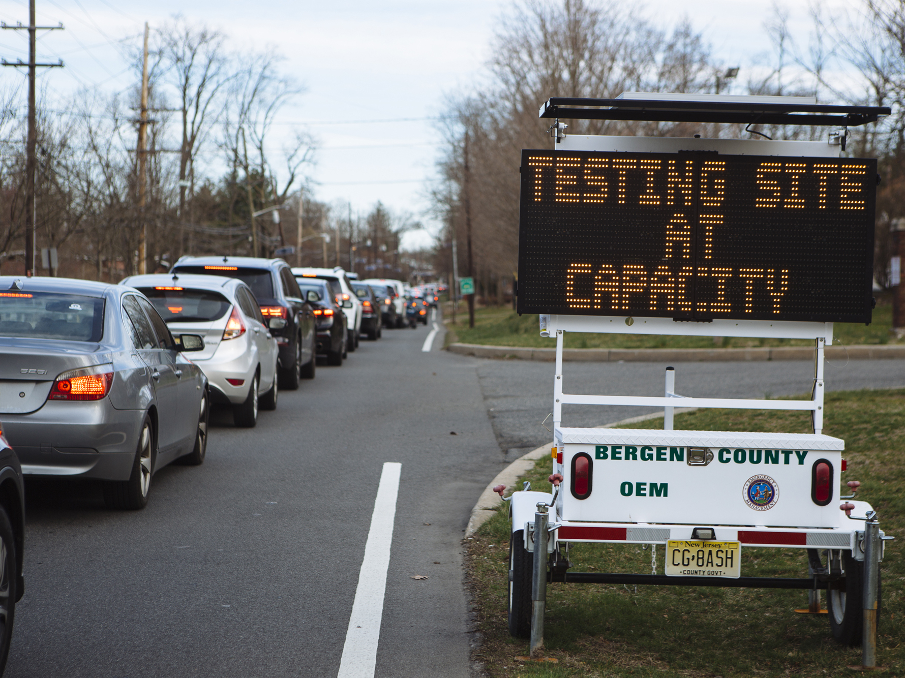 caption: People wait in their vehicles for coronavirus testing at Bergen Community College in Paramus, N.J., last month.