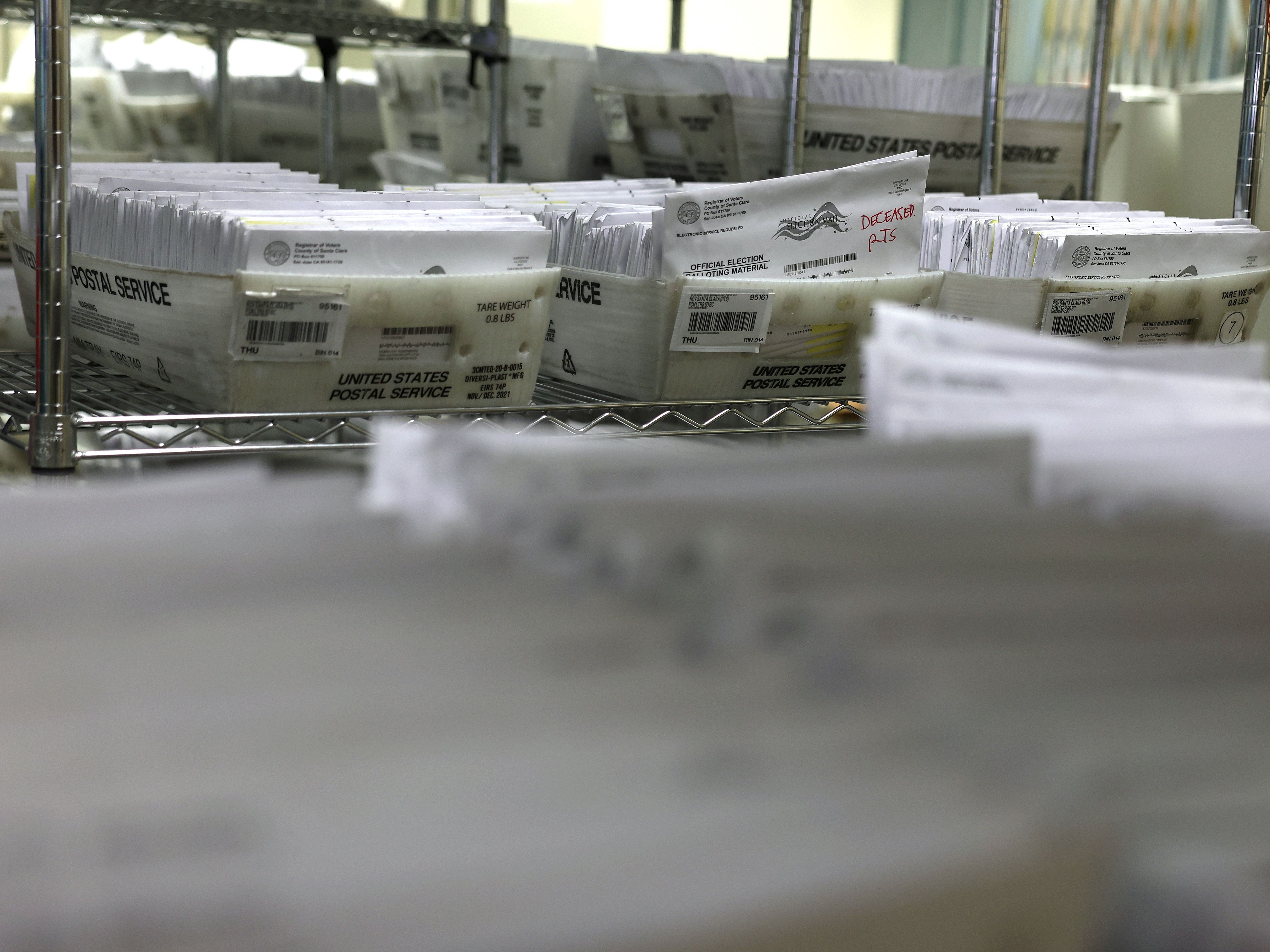 caption: Trays of mail in ballots are stacked at the Santa Clara County Registrar of Voters office on Oct. 21, 2024 in San Jose, Calif.
