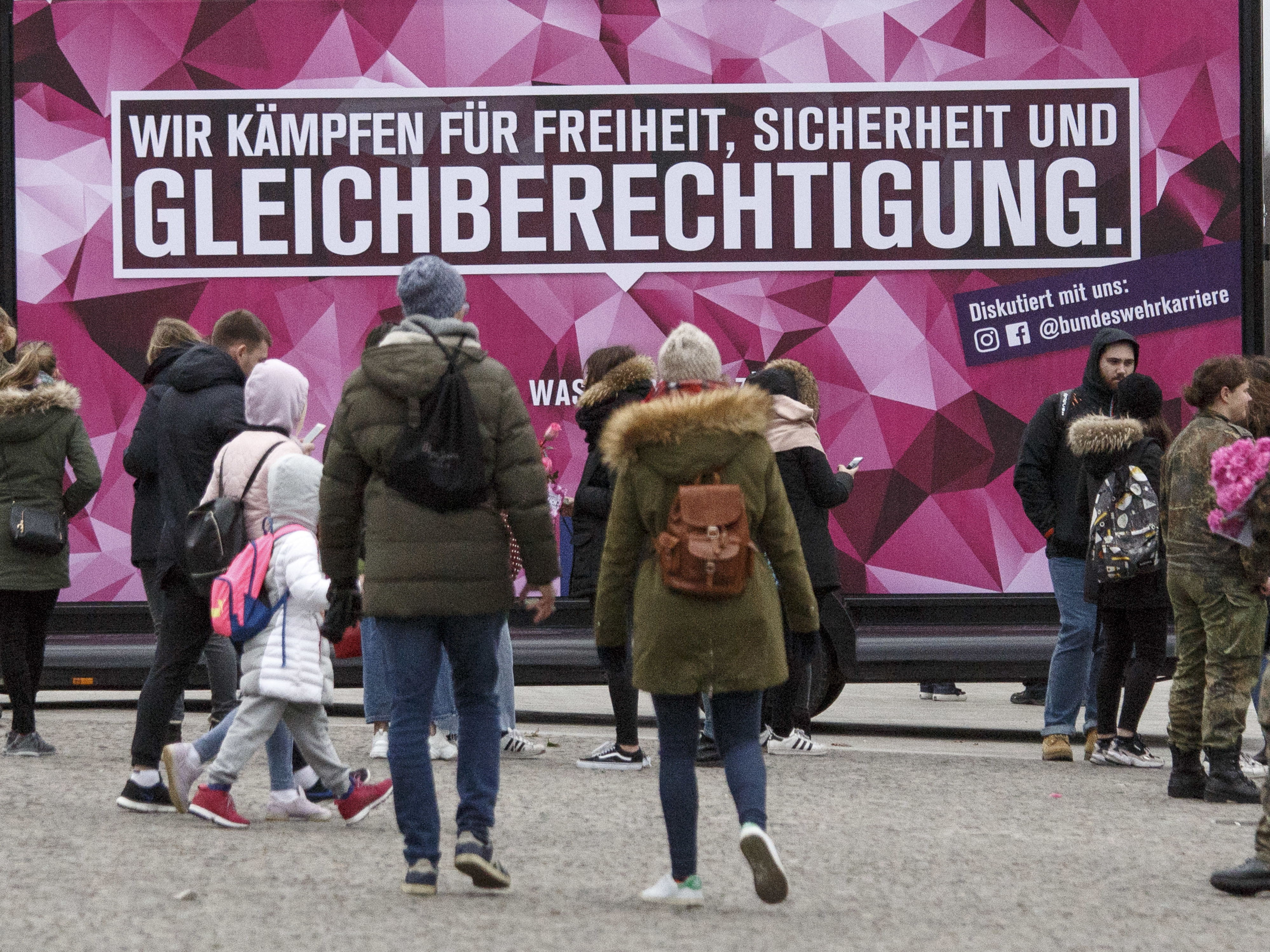 caption: People pass a banner that reads: "We fight for freedom, security and equal rights" in front of the  Brandenburg Gate on Friday in Berlin.