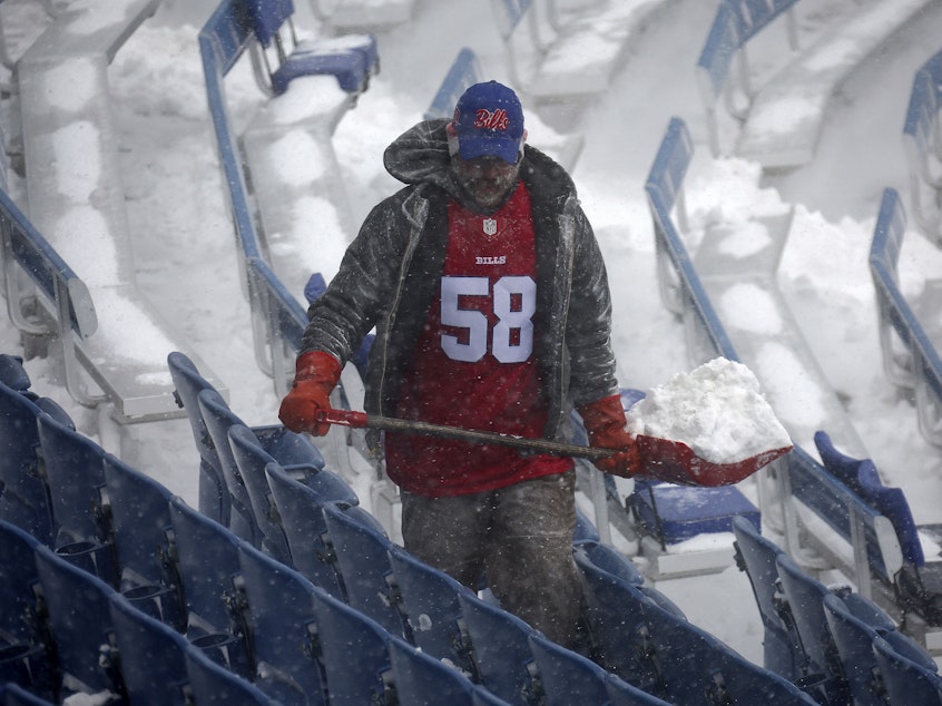 caption: A worker helps remove snow from Highmark Stadium in Orchard Park, N.Y., Sunday Jan. 14, 2024. A potentially dangerous snowstorm that hit the Buffalo region on Saturday led the NFL to push back the Bills wild-card playoff game against the Pittsburgh Steelers from Sunday to Monday.