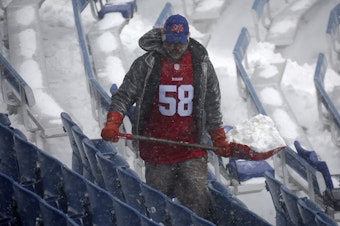 caption: A worker helps remove snow from Highmark Stadium in Orchard Park, N.Y., Sunday Jan. 14, 2024. A potentially dangerous snowstorm that hit the Buffalo region on Saturday led the NFL to push back the Bills wild-card playoff game against the Pittsburgh Steelers from Sunday to Monday.