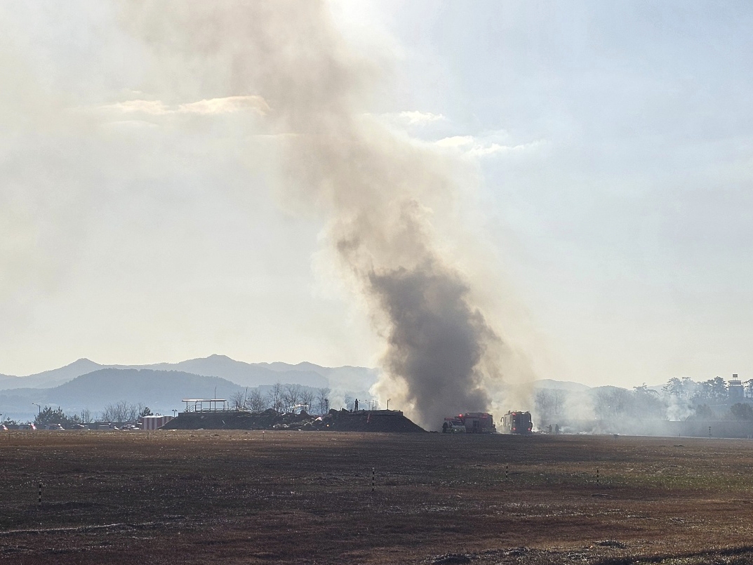 caption: Firefighters work to extinguish a fire off the runway of Muan International Airport in Muan, South Korea, Sunday, Dec. 29, 2024. (Maeng Dae-hwan/Newsis via AP)