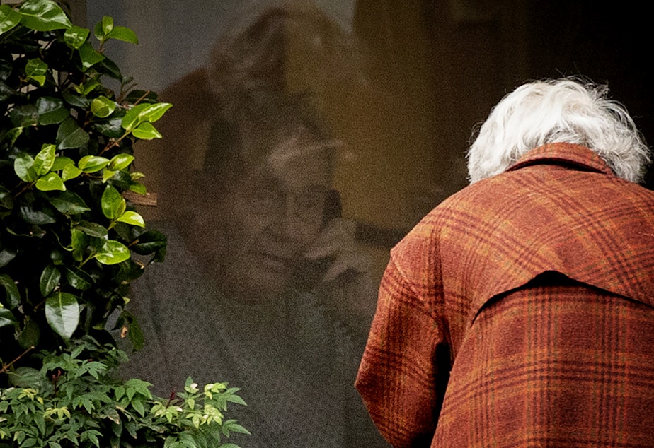 caption: Dorothy Campbell talks to her husband, Gene Campbell, on the phone through his window at the Life Care Center of Kirkland on Thursday, March 5, 2020, in Kirkland. Dorothy's son Charlie Campbell came all the way from Silver City, New Mexico, to bring his mother to see his father. "It’s kind of tough but it’s the best we can do at this point," he said. 