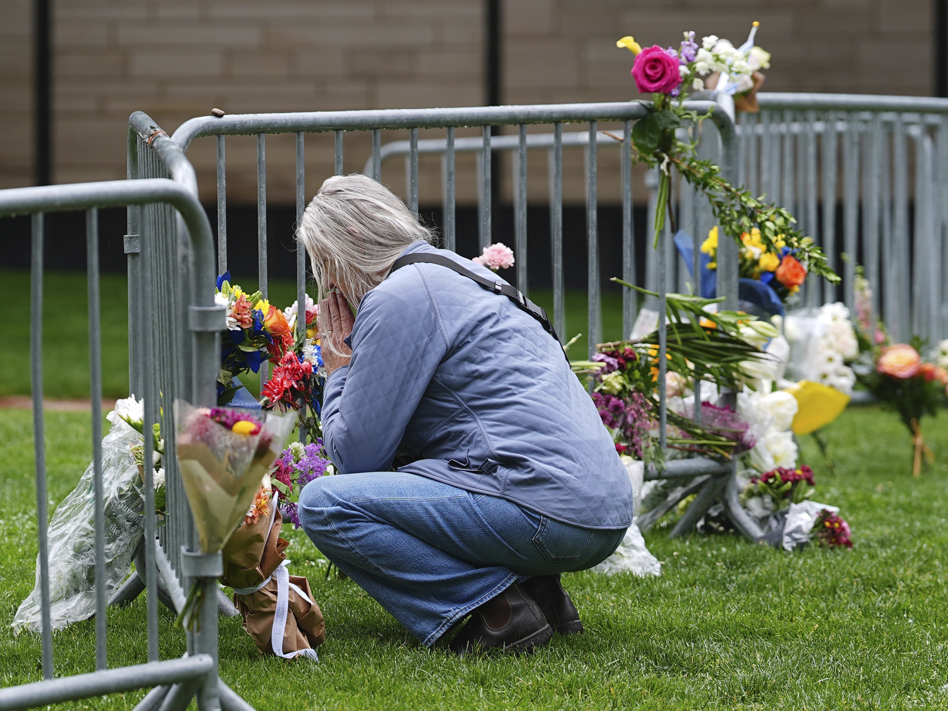 caption: A visitor offers a tribute after leaving a bouquet of flowers at a makeshift memorial for victims of an attack outside of the Boulder County, Colo., courthouse as a light rain falls Tuesday, June 3, 2025, in Boulder, Colo. (AP Photo/David Zalubowski)