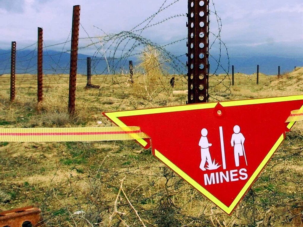 caption: An international sign warning about mines hangs beside a minefield at Bagram Air Base in Afghanistan in 2002.