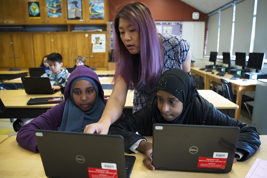 caption: Janet Bautista, center, helps 7th-grade students Amira Ismail, left, and Fahima Abdi, right, with an assignment about chemical reactions during science class on Thursday, March 28, 2019, at Asa Mercer Middle School in Seattle. 