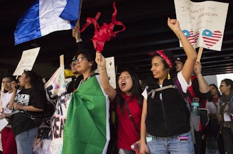 caption: Suri Emigdio, 11, second from right, and Rocio Carranza, right, cheer during the annual March for Immigrant and Workers Rights on Tuesday, May 1, 2018, in Seattle. Tap or click on the first image to see more.  