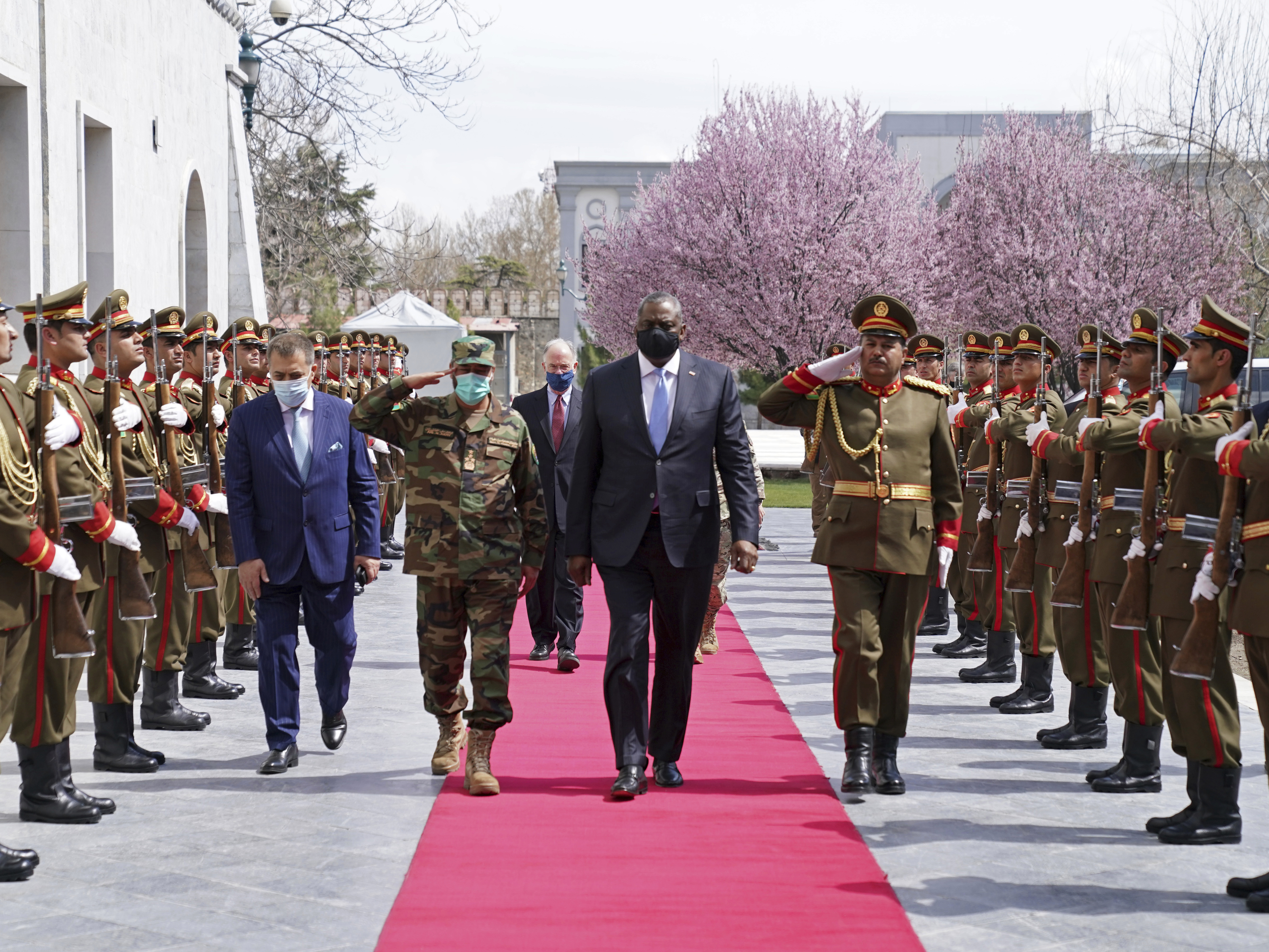 caption: U.S. Defense Secretary Lloyd Austin (center) reviews an honor guard at Afghanistan's presidential palace in Kabul on March 21. President Biden says all U.S. troops will leave Afghanistan by September, though the Americans will still assist from "over the horizon."