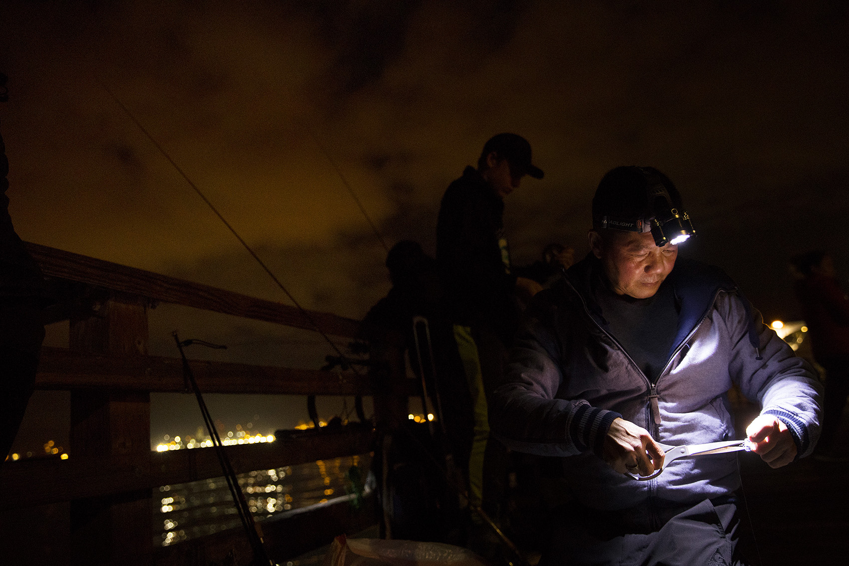 caption: Billy Nguyen adjusts his squid jig on Friday, October 26, 2018, while squidding at Seacrest Park Pier in Seattle. 