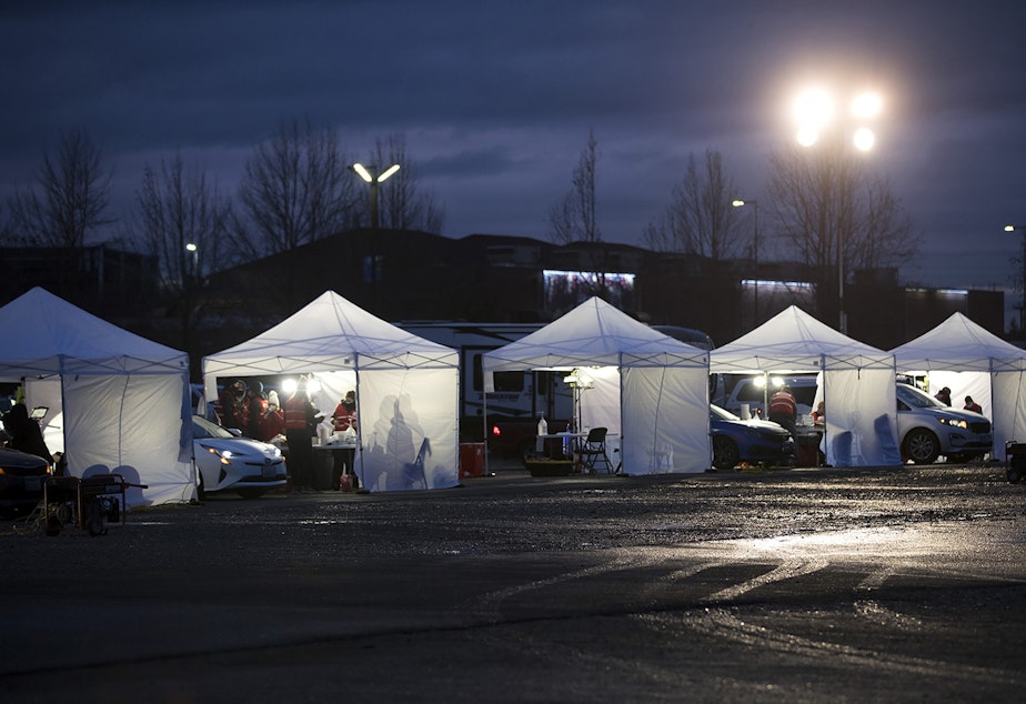caption: A line of vaccine tents are lit up as the sun goes down on Thursday, January 28, 2021, during a free drive-thru Covid-19 vaccination clinic at the Washington State Fair Events Center in Puyallup. The clinic vaccinated approximately 2,000 people in phases 1A and 1B of the state’s vaccination plan on Thursday. 