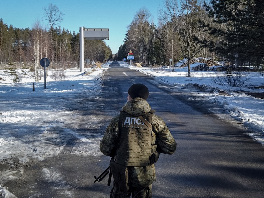 caption: A member of the Ukrainian State Border Guard stands watch at the border crossing between Ukraine and Belarus on Saturday.