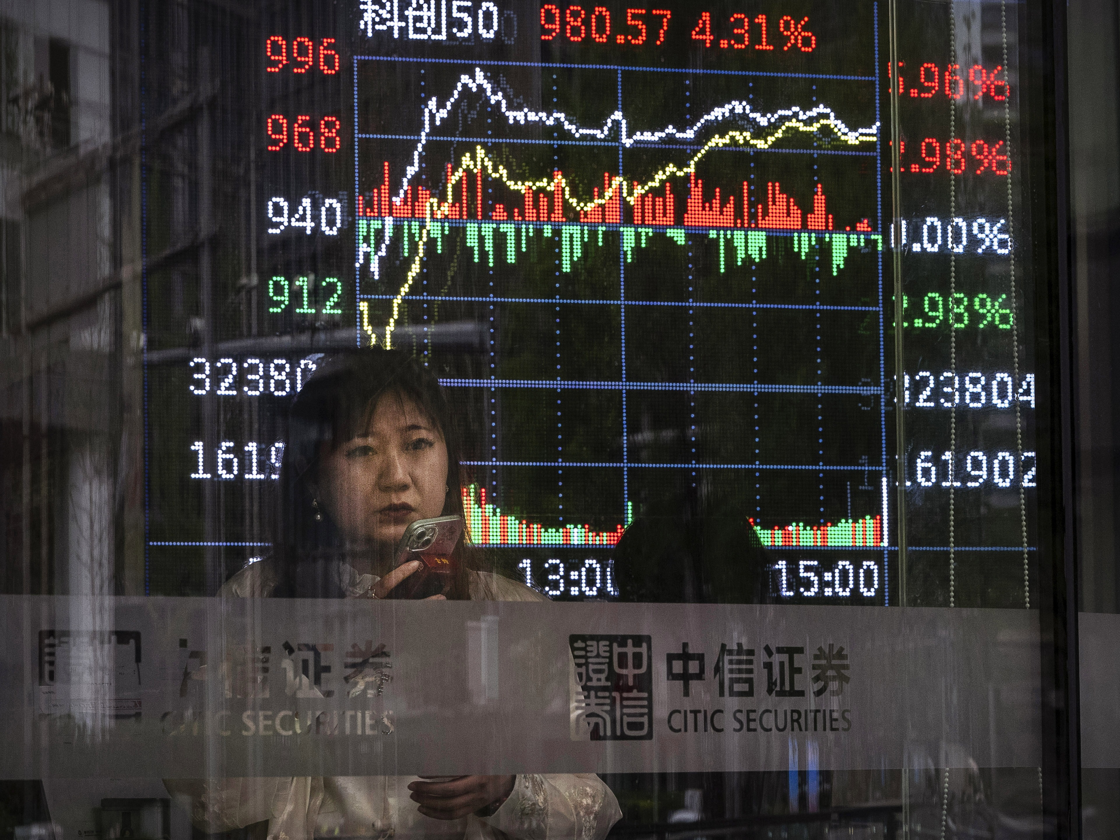 caption: A stock ticker shows trading at a securities firm in Beijing April 9.