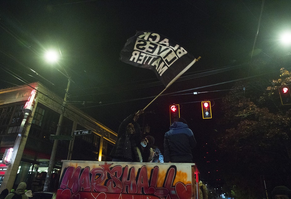 caption: Vonn Wright, also known as Fairy Vonn Mother, waves a Black Lives Matter flag on Monday, October 26, 2020, during the 150th day of protests for racial justice in Seattle at the intersection of East Pine Street and Broadway. 