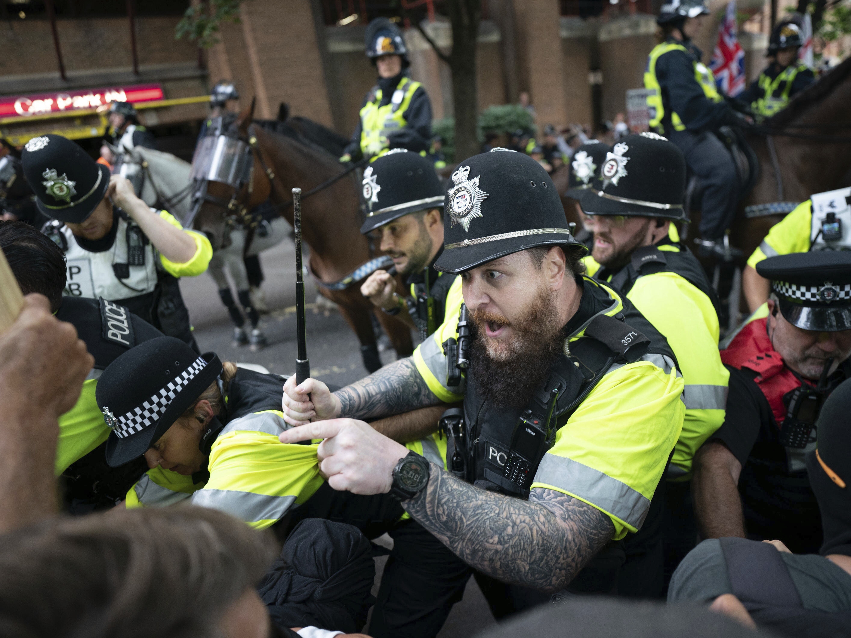 caption: Mounted police officers scuffle with demonstrators during a protest by anti-migrant Abolish Asylum System and counter protesters at Castle Park in Bristol, England on Saturday.