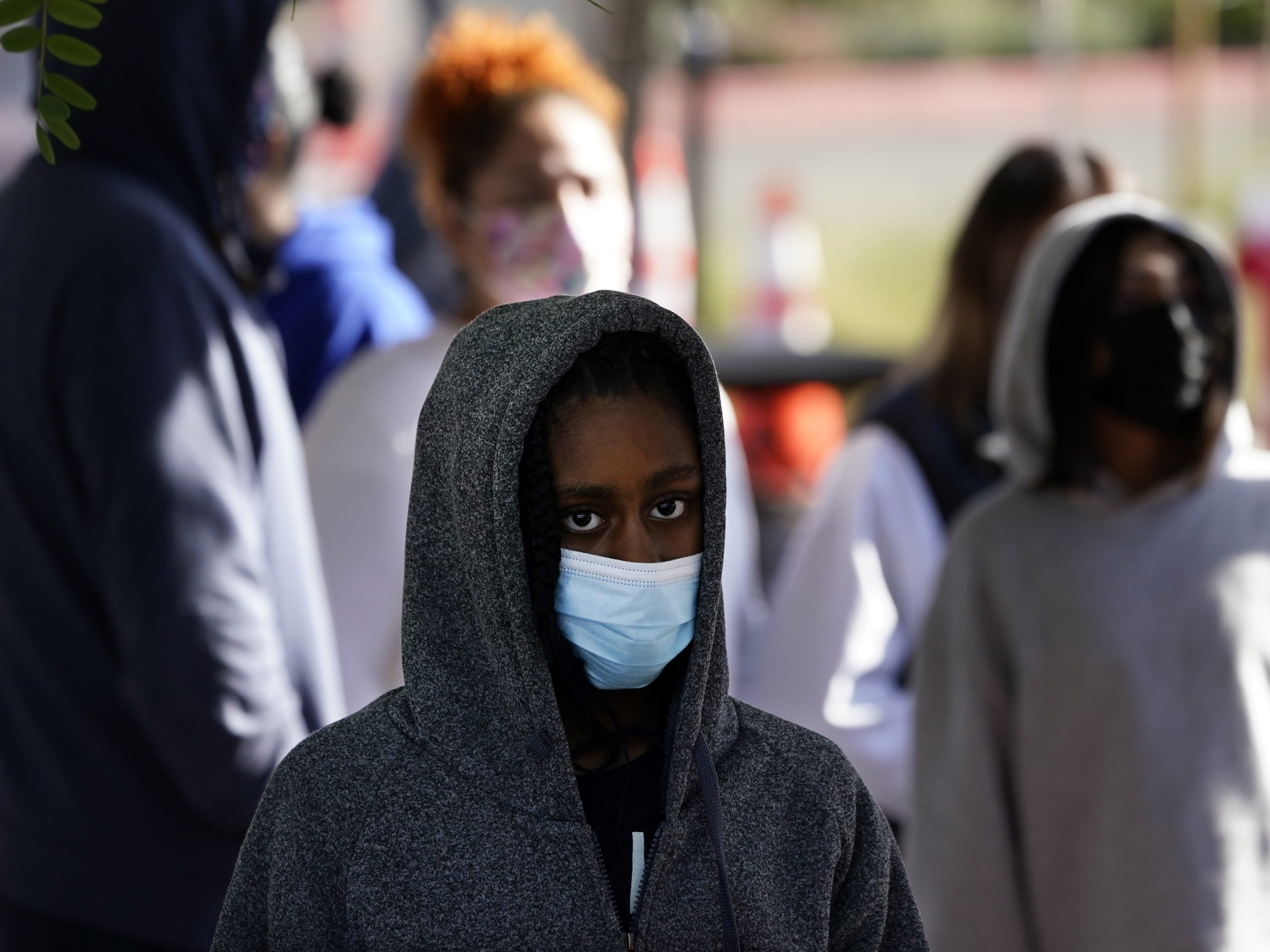 caption: A young person wears a mask while waiting in line at a COVID-19 testing site on the Martin Luther King Jr. medical campus on Monday in Los Angeles.
