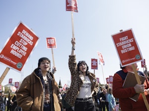 caption: Marchers raise picket signs during a "Fight Starbucks' Union Busting" rally held in Seattle in April.