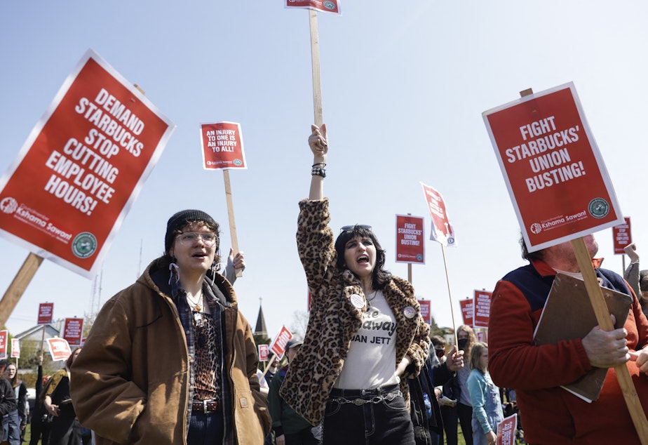 caption: Marchers raise picket signs during a "Fight Starbucks' Union Busting" rally held in Seattle in April.