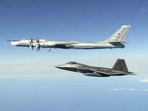 caption: In this image taken June 16, 2020, and released by the North American Aerospace Defense Command, a Russian Tu-95 bomber (top) is intercepted by a U.S. F-22 Raptor fighter off the coast of Alaska. Russian nuclear-capable strategic bombers have flown near Alaska on a mission demonstrating the military's long-range strike capability.
