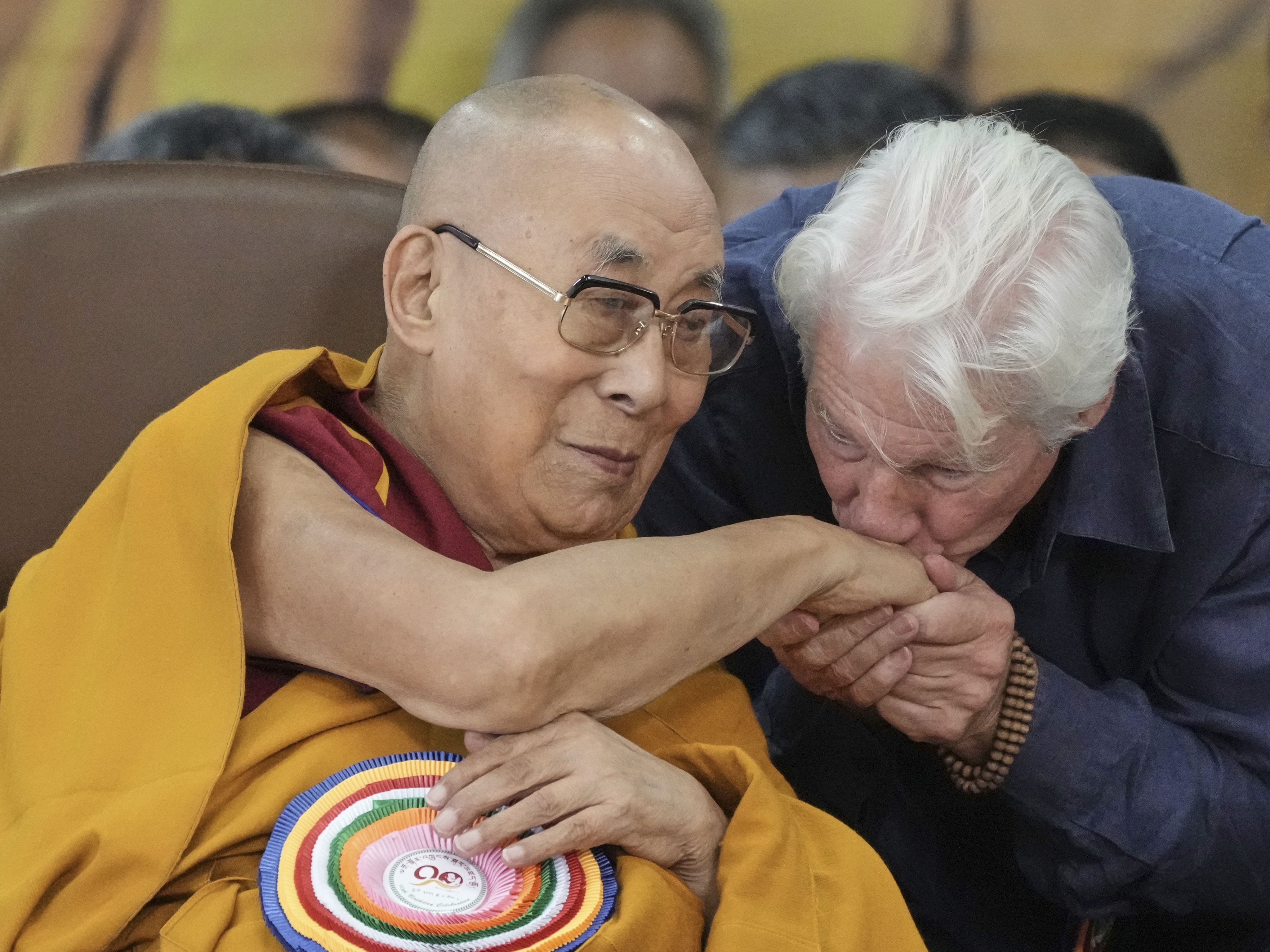caption: Actor Richard Gere, right, kisses the hand of Tibetan spiritual leader the Dalai Lama at an event celebrating the Dalai Lama's 90th birthday in Dharamshala, India, Sunday.