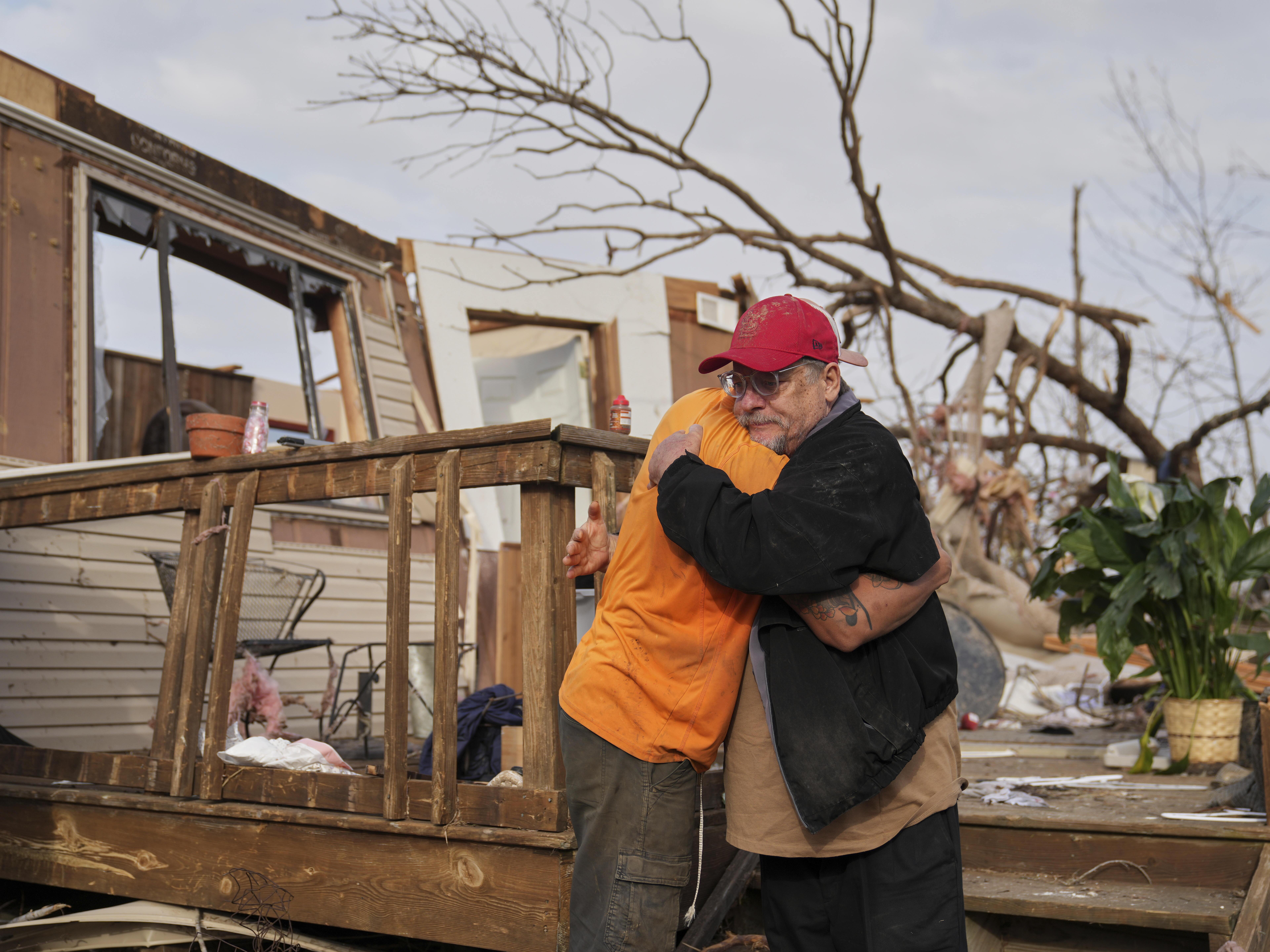 caption: Tim Scott, right, gets a hug from friend Jorden Harris outside Scott's home he was inside when it was destroyed during a severe storm the evening before Saturday, March 15, 2025, in Wayne County, Mo.