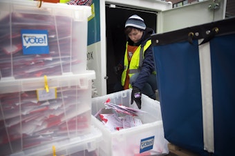 caption: King County Elections employee Josephine Ruff unloads a  full ballot drop box outside of the Seattle Public Library on Tuesday, November 7, 2017, in Ballard. 