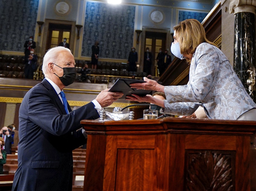 caption: President Biden hands a copy of his speech to House Speaker Nancy Pelosi as he arrives to address a joint session of Congress in 2021.