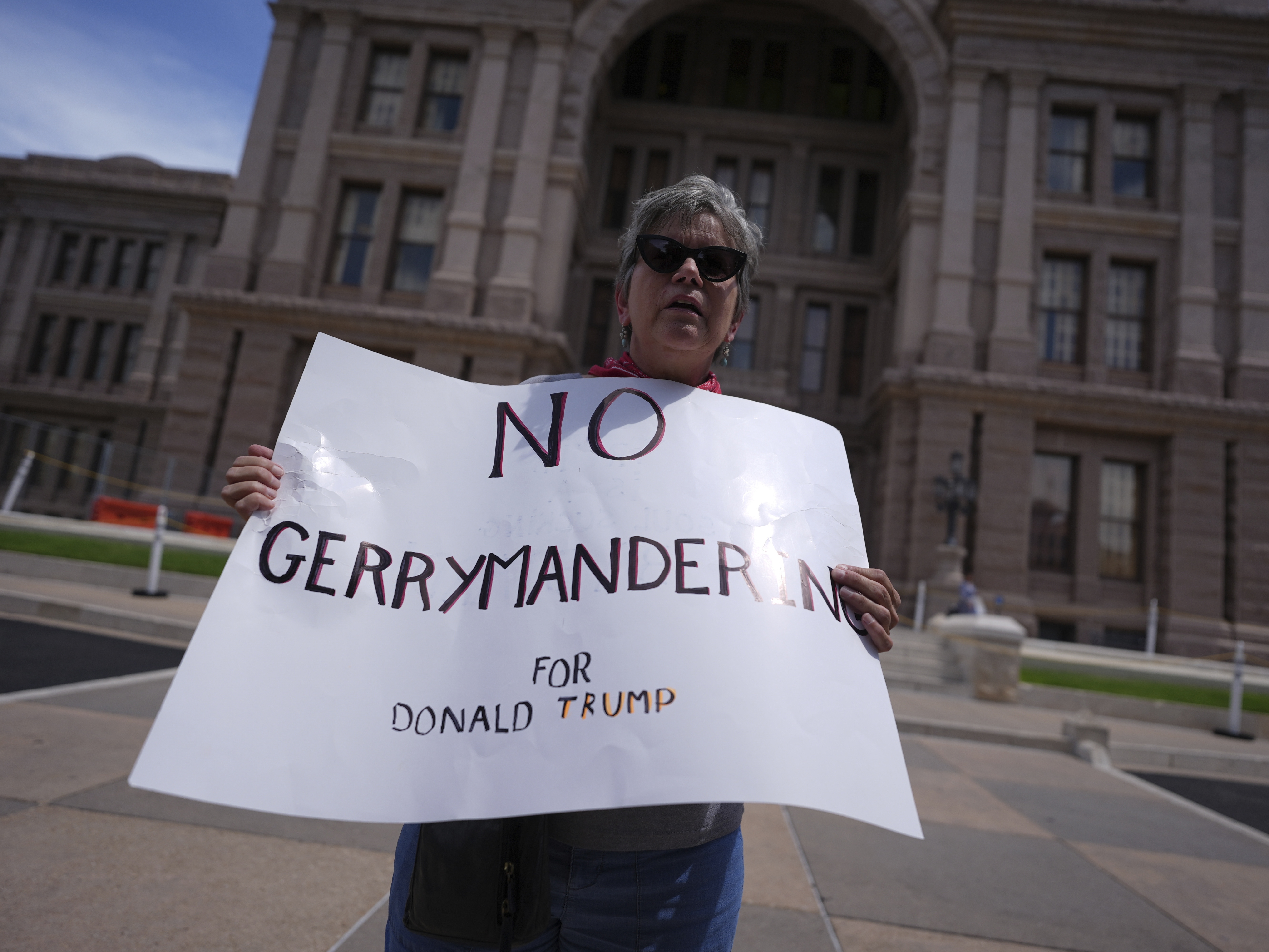 caption: A demonstrator holds a sign saying "NO GERRYMANDERING FOR DONALD TRUMP" outside the Texas Capitol in Austin on Monday as state lawmakers gather for a special session to redraw congressional voting districts.