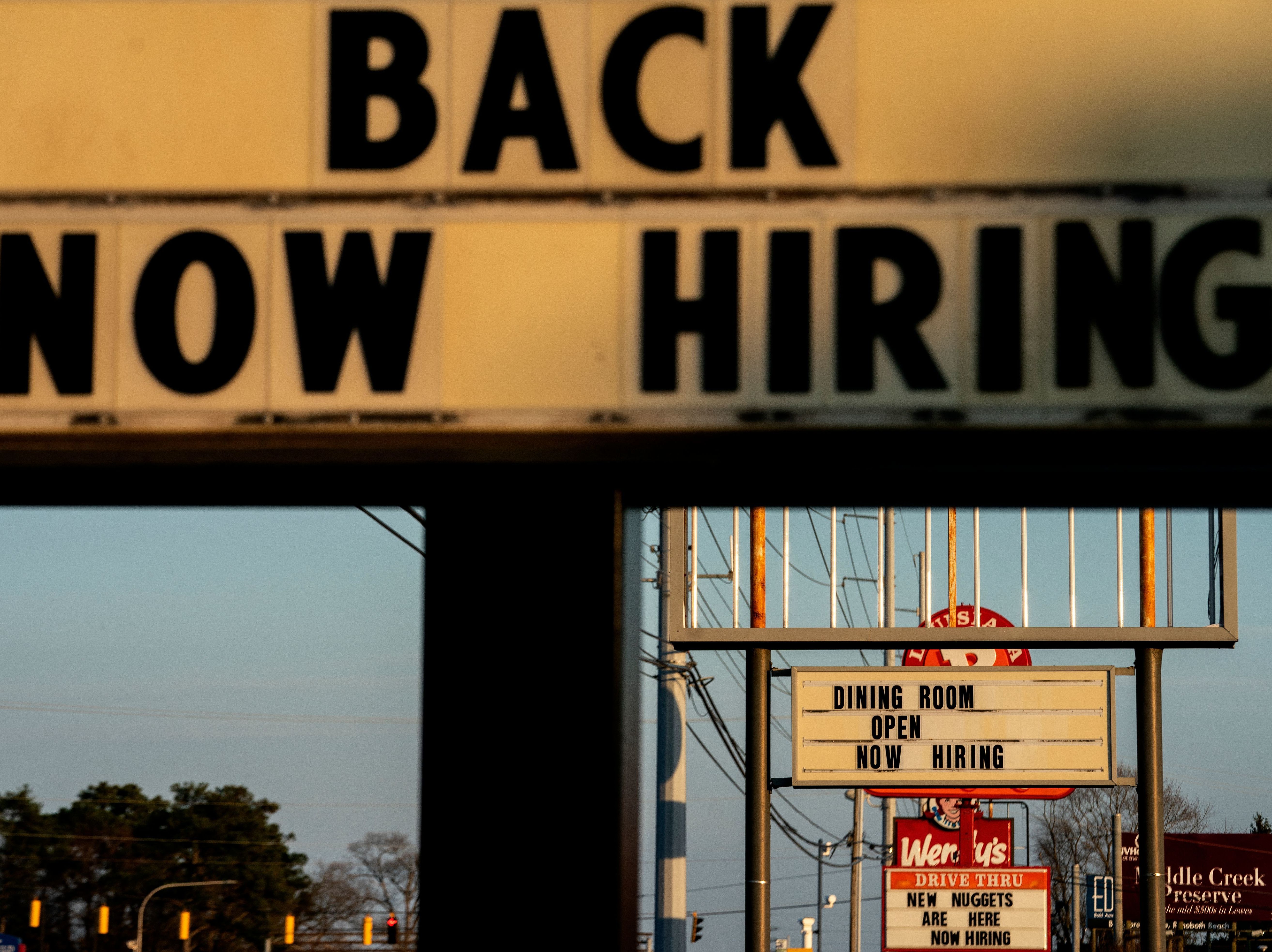 caption: Signs with the message 'Now Hiring' are displayed in front of restaurants in Rehoboth Beach, Delaware, on March 19.