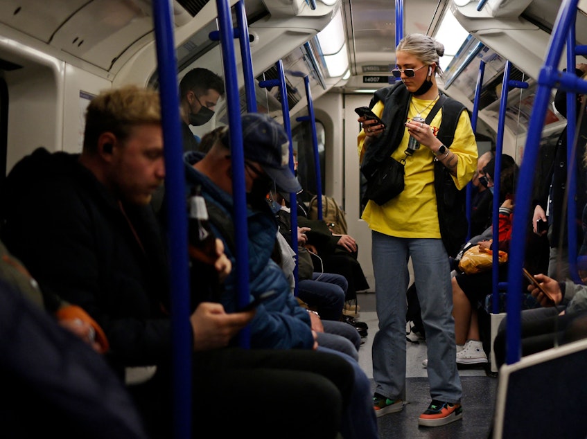 caption: Passengers, some wearing protective face coverings and some not, travel during rush hour on the London Underground last month.