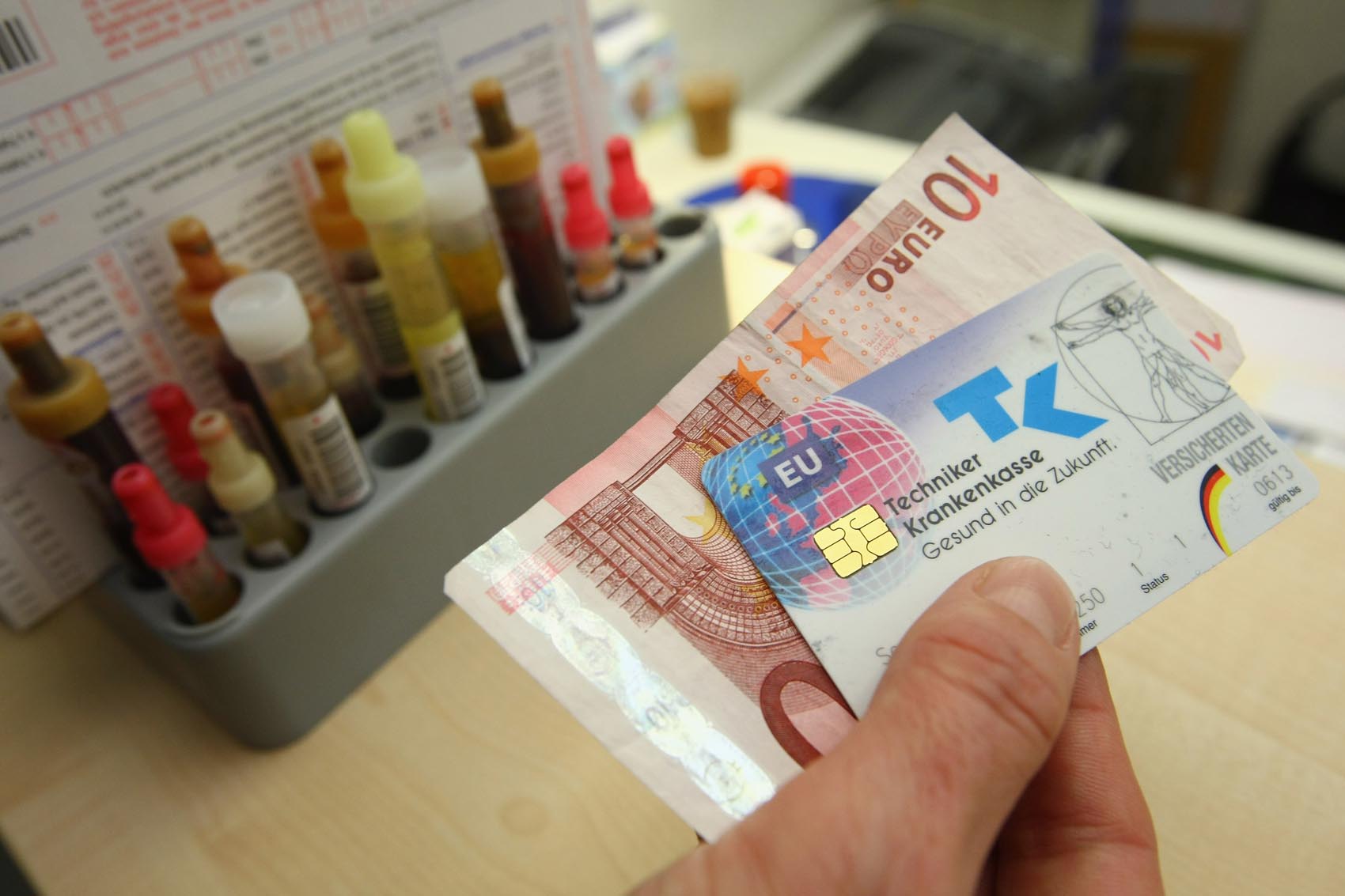 caption: A secretary accepts 10 euros and a public health insurance card in Berlin, Germany. (Sean Gallup/Getty Images)
