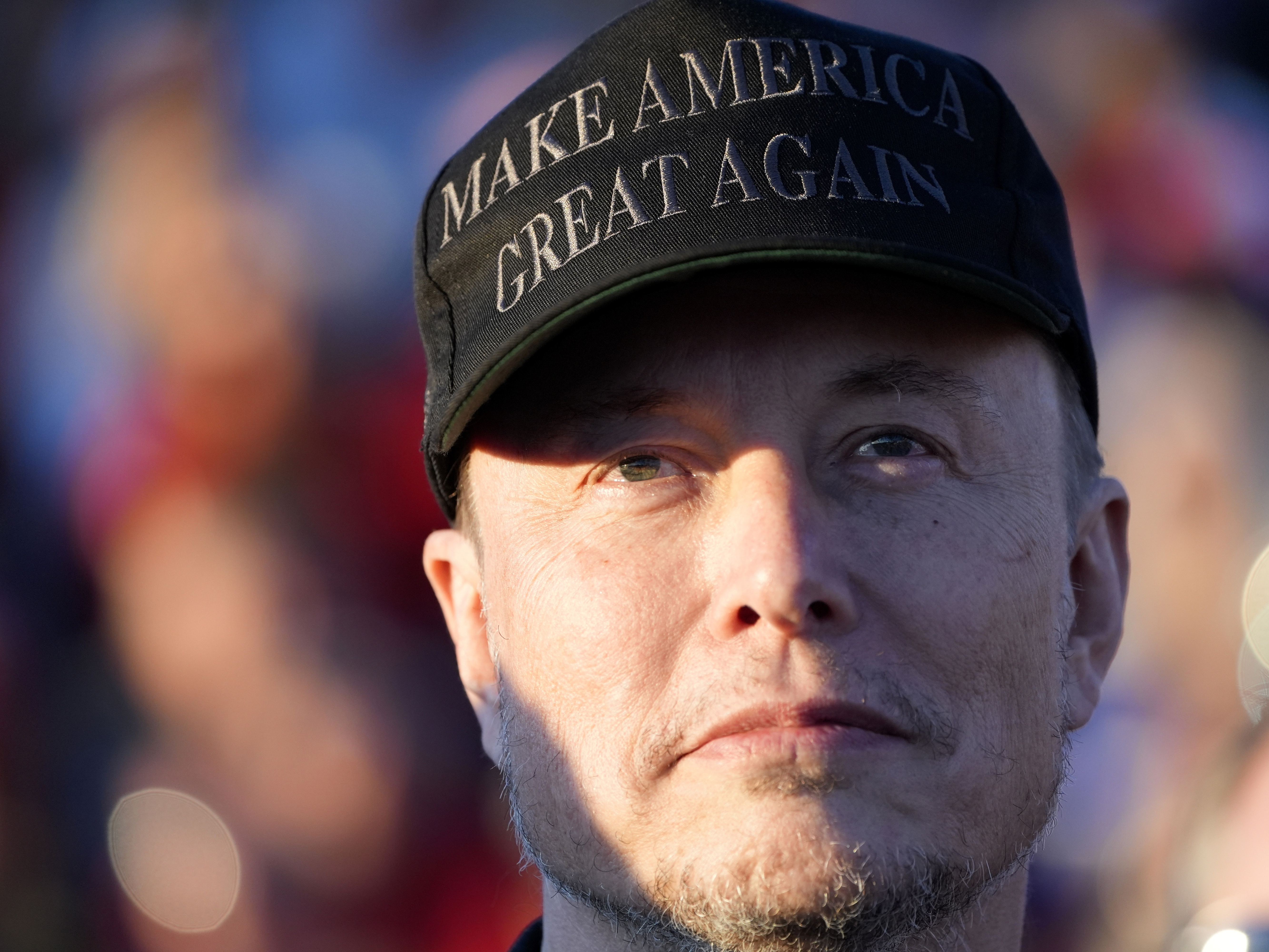 caption: Tesla and SpaceX CEO Elon Musk listens as Republican presidential nominee former President Donald Trump speaks at a campaign event in Butler, Pa., on Oct. 5.