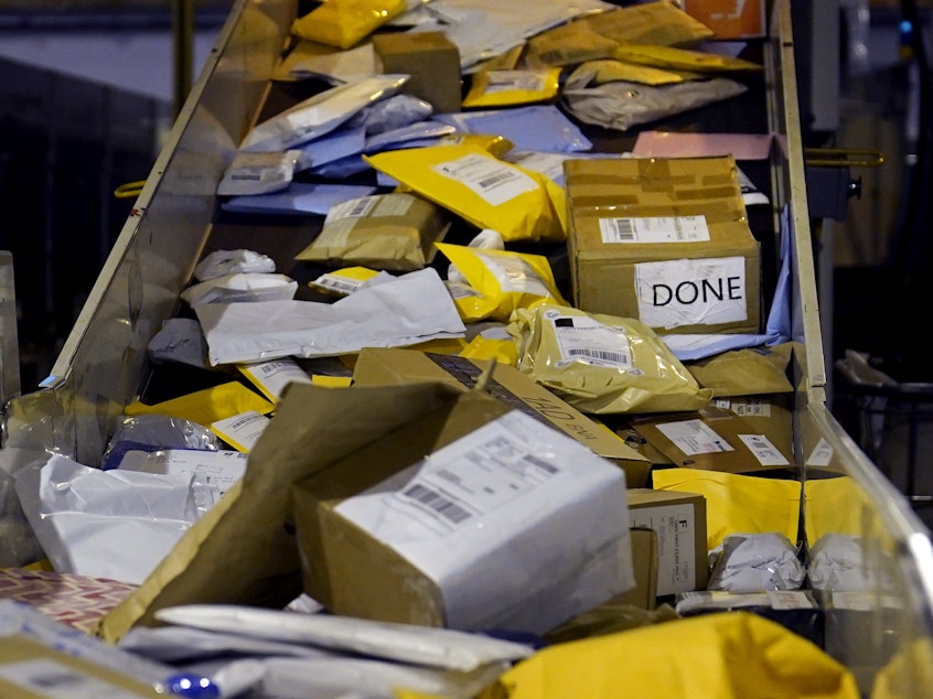 caption: Parcels jam a conveyor belt at the United States Postal Service sorting and processing facility in Boston.