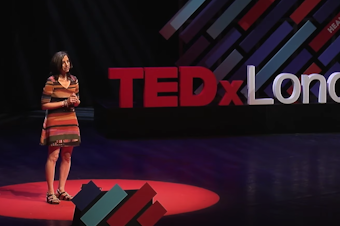 caption: Beth Gardiner speaks on the TEDx stage in London.