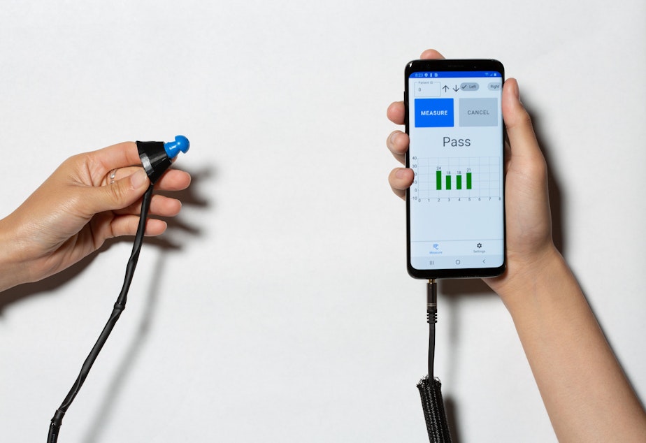 caption: Hearing test earbud and smartphone.
