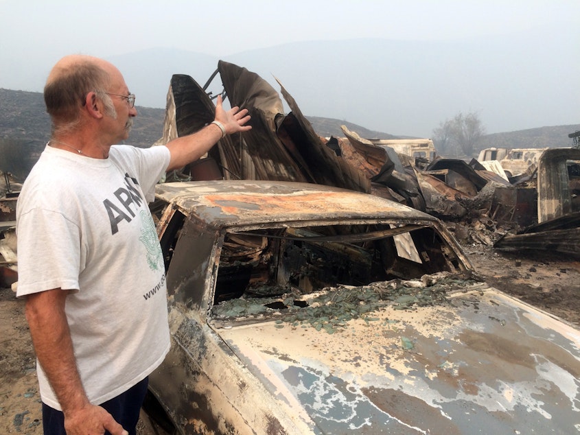 caption: Steve Surgeon surveys the ruins after he lost outbuildings and vehicles in a wildfire on the outskirts of Okanogan, Wash., Sunday, Aug. 23, 2015. His home was saved , though.