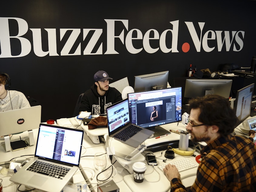caption: Members of the BuzzFeed News team work at their desks at BuzzFeed headquarters on Dec. 11, 2018.