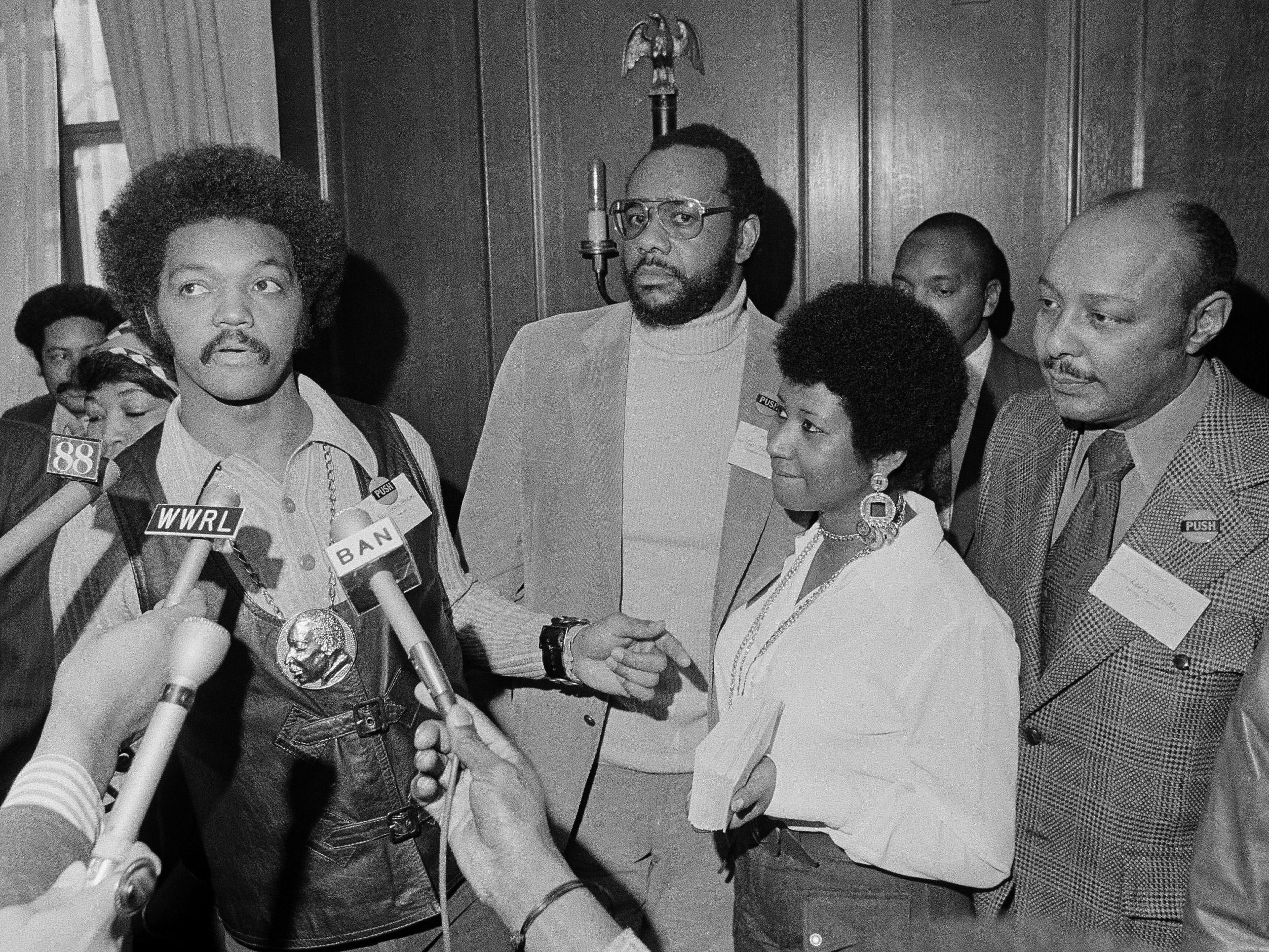 caption: This March 26, 1972 file photo shows the Rev. Jesse Jackson speaking to reporters at the Operation PUSH Soul Picnic in New York as Tom Todd, vice president of PUSH, from second left, Aretha Franklin and Louis Stokes.