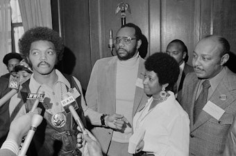 caption: This March 26, 1972 file photo shows the Rev. Jesse Jackson speaking to reporters at the Operation PUSH Soul Picnic in New York as Tom Todd, vice president of PUSH, from second left, Aretha Franklin and Louis Stokes.