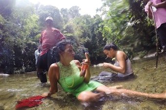 caption: Marta Amaro and Liset Barrios take a minute to rest after crossing a river in the Darien Gap, the untamed jungle that engulfs the Colombia-Panama border. Photographer Lisette Poole went with them to document their journey north.