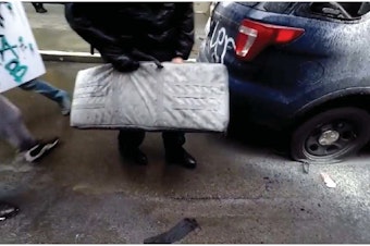 caption: Federal charging documents allege that this frame from a Youtube video depicts the theft of an SPD rifle in downtown Seattle on May 30, 2020. 