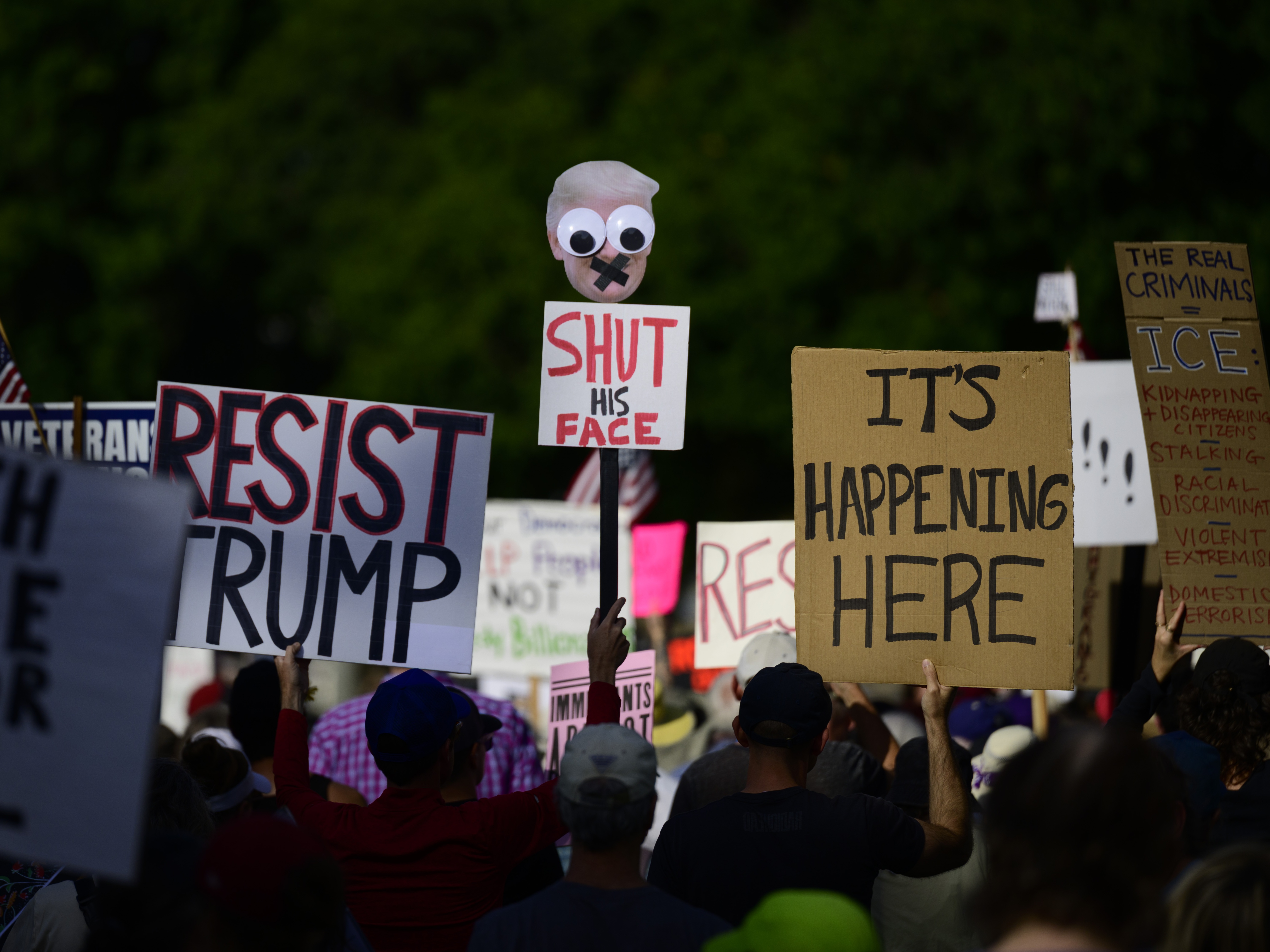 caption: People hold signs during a protest on Sunday in Portland, Ore.