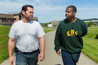 caption: Diontae Moore-Lyons, 17, right, is escorted back to his unit by manager Shawn Northcutt at Green Hill School in Chehalis, Wash., on Wednesday, May 10, 2017. Green Hill School is a medium/maximum security, fenced facility for teenage male offenders.