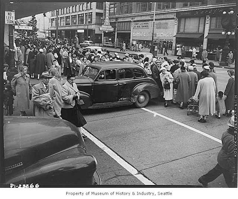 caption: Shoppers cross Fifth Avenue in Seattle during the Christmas season, 1954.