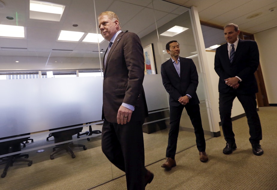 caption: Seattle Mayor Ed Murray, left, walks past his husband, Michael Shiosaki, center, and his attorney, Bob Sulkin, to make a statement to media members Friday, April 7, 2017, in Seattle. 