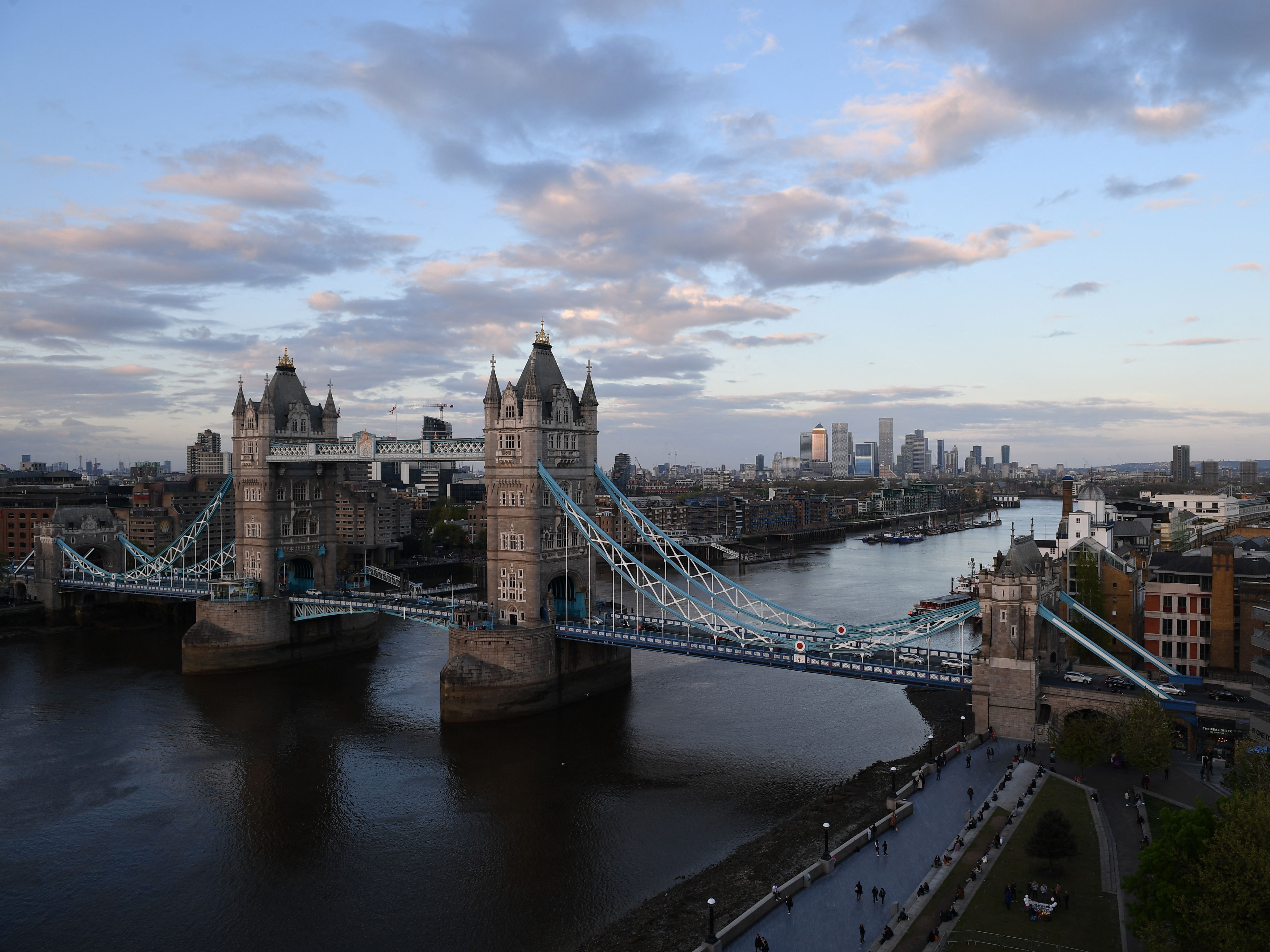 caption: Tower Bridge over The River Thames and, in the distance, the secondary central business district of Canary Wharf are pictured as the sun sets in London.